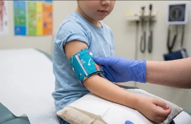 A pediatric blood pressure cuff on a young child's arm